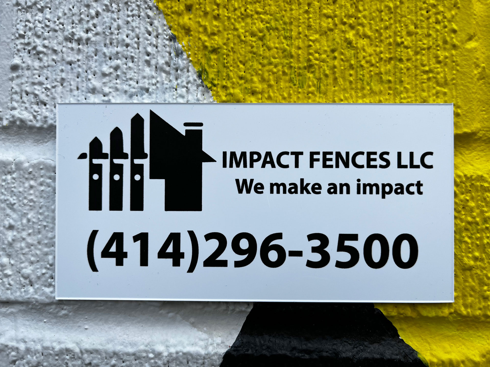 White custom plastic fence plate for Impact Fences LLC with black fence-and-house logo, tagline 'We make an impact', and phone number 414-296-3500